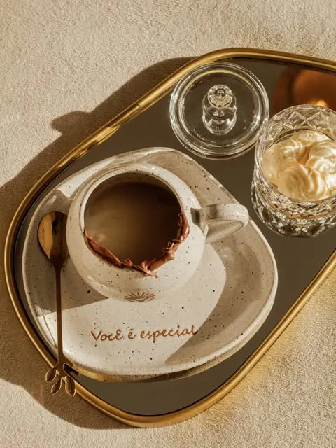 Xícara de café com a frase Você é especial no pires, servida em uma bandeja dourada com chantilly ao lado
