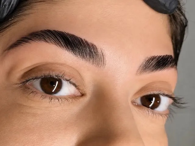 Close de sobrancelhas depois da brow lamination: fios alinhados e penteados para cima, sobre olhos castanhos